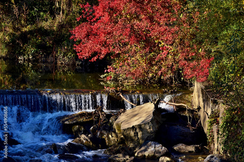 Ein kleiner Wasserfall von herbstlich gefärbten Gebüsch eingerahmt photo