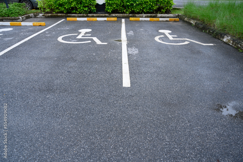Obraz premium White handicapped symbol painted on asphalt floor special lane parking. Disabled parking spaces. traffic sign about handicaps.
