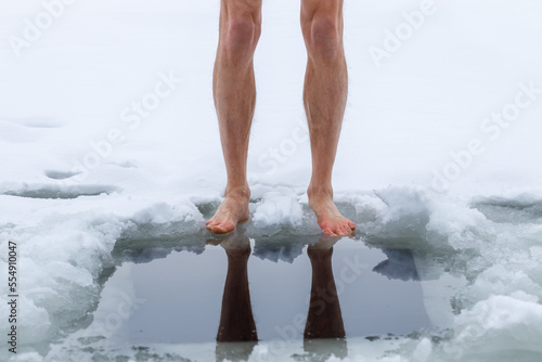 Winter hardening in cold water. Men's legs and a hole close-up.