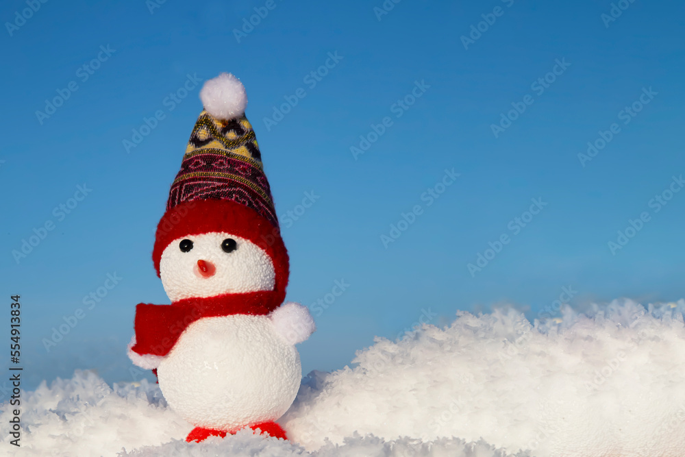 Obraz premium A happy snowman stands in the snow on a blue background. Winter fairy tale