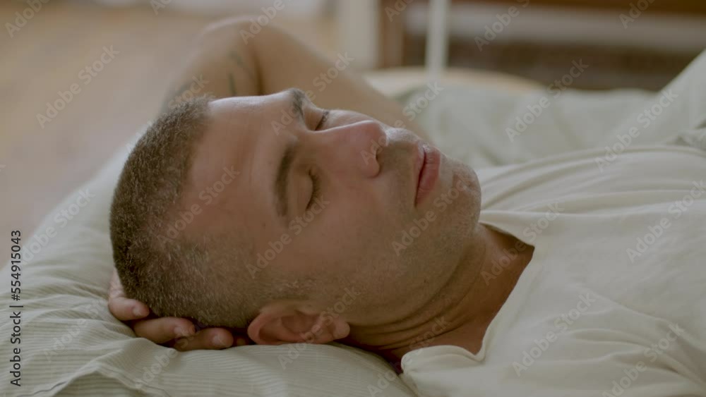 Peaceful Caucasian man sleeping in morning with hand behind head. Close-up shot of handsome man lying in bed, relaxing and resting at home, regenerating energy. Sleep cycle, health care concept Peaceful Caucasian man sleeping in morning with hand behind head. Close-up shot of handsome man lying in bed, relaxing and resting at home, regenerating energy. Sleep cycle, health care concept