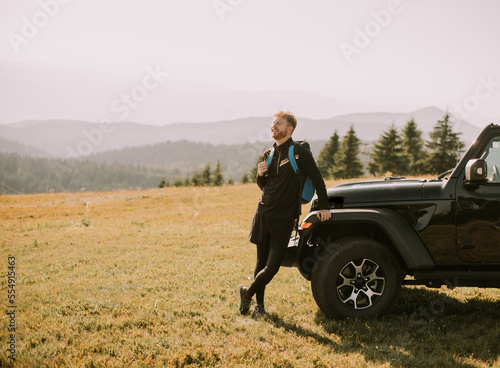 Young man relaxing by the terrain vehicle hood at countryside