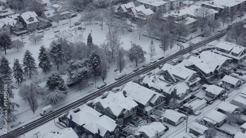 Fly over Vancouver disctrict with house roofs in snow and cars on a snowy road photo