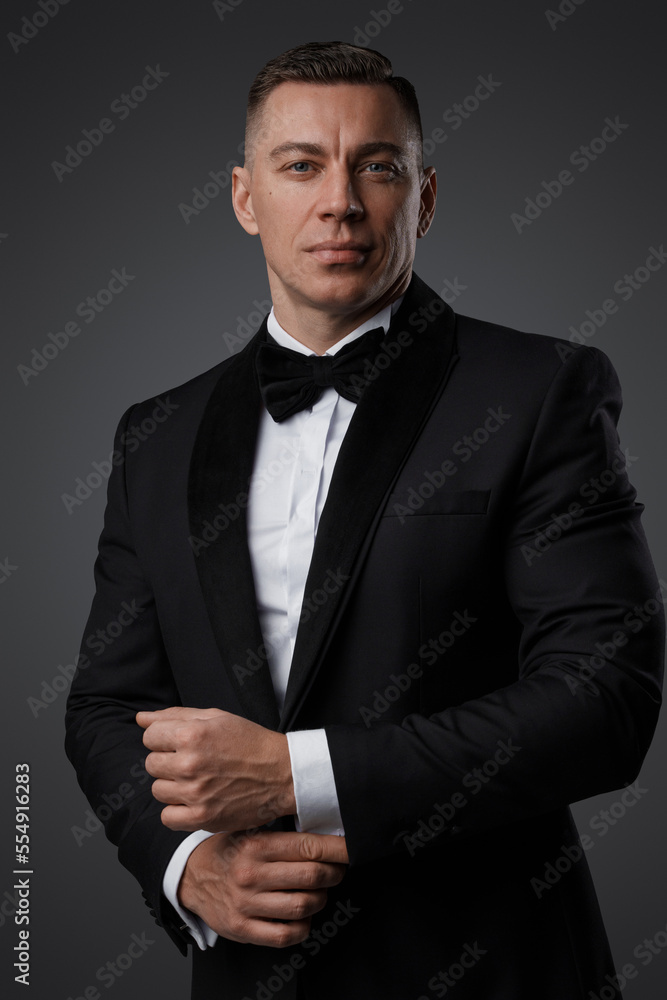 Portrait of handsome man dressed in stylish black suit staring at camera.