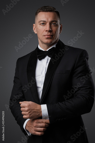 Portrait of handsome man dressed in stylish black suit staring at camera.