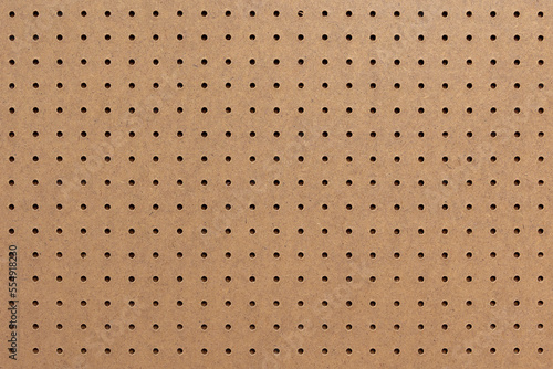 Abstract background of brown perforated hardboard sheet, Plywood with pre-drilled with evenly spaced holes Nature seamless pattern texture, Surface and details of brown wood plank. photo