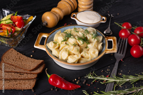 boiled dumplings with sour cream and gray bread, on a black background