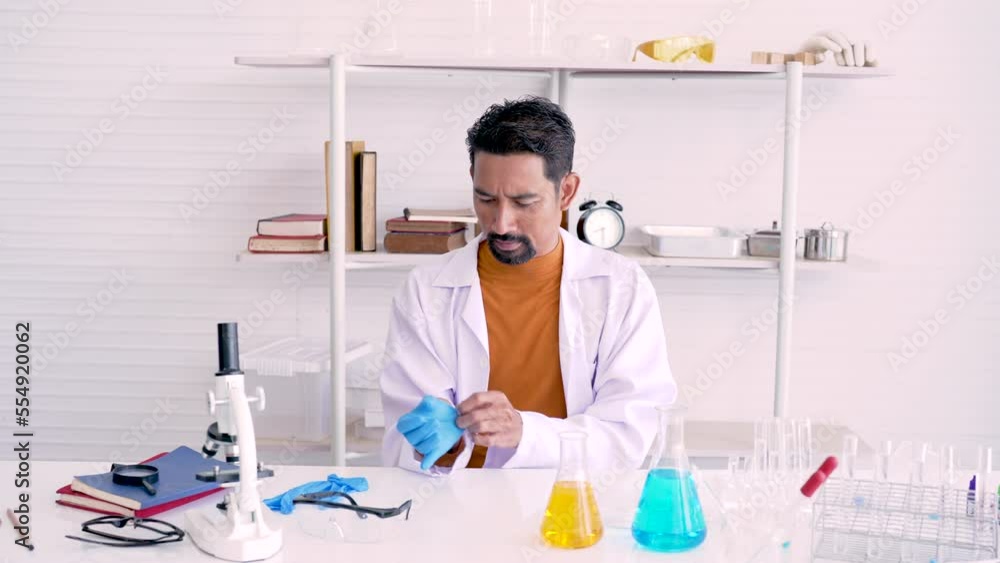 4K, dark-faced male teacher science, Sitting wearing gloves, used for scientific experiments, For safety cleanliness in lab experiments, experiments must be conducted in front children, in classroom. 4K, dark-faced male teacher science, Sitting wearing gloves, used for scientific experiments, For safety cleanliness in lab experiments, experiments must be conducted in front children, in classroom.