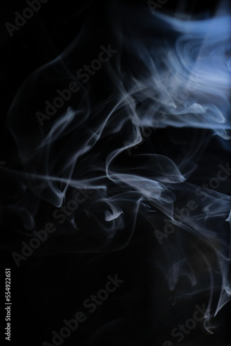 Graceful swirls of white smoke isolated from black background. Close-up of vapor. Soft focus and texture from vintage Helios 44m-4 lens. Abstract graphic design asset. Vertical copy space.