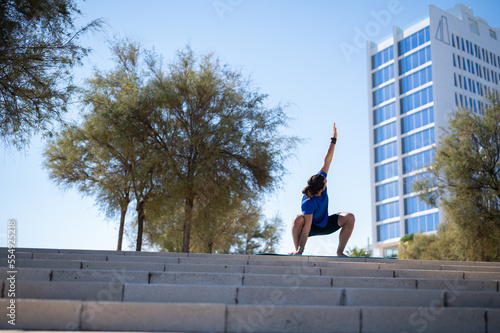 Young man with beard and ponytail performing stretching exercises in an urban environment. Sports concept.