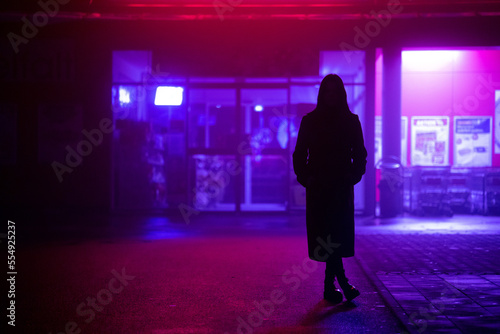 dark silhouette of a girl dressed in a long coat against the background of a nig Fototapet