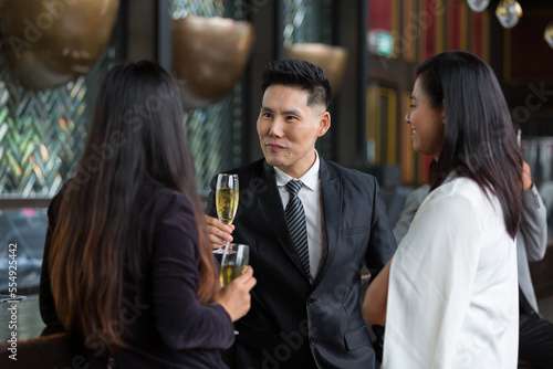 Asian business man and woman or partnership holding glass of beer and drinking discussing project work in the office work space