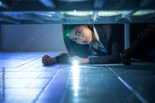 woman looking under bed Use a flashlight to look for something under the bed. There was something unusual in the darkness under the bed photo