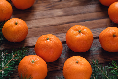 Fresh ripe clementines or mandearine oranges and fir tree branches on a dark woden board. Christmas food. Copy space.