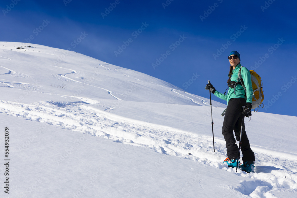 Woman backcountry skiing, climbing up mountain in skin track, on AT skis and skins in Hatcher's Pass, Alaska, Talkeetna Mountains; Alaska, United States of America