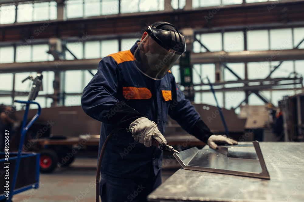 Factory worker polishing a metal part Factory worker polishing a metal part