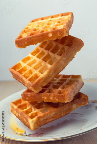 Vertical view of flying waffles on a plate with white board photo