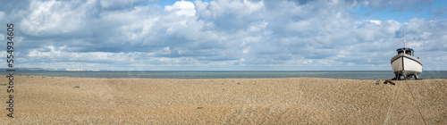 Wooden cabin boat tethered on the shingle beach at Dungeness along the Atlantic Coast; Dungeness, Kent, England, United Kingdom