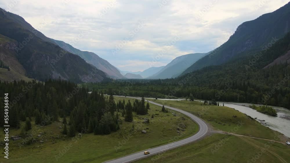 Aerial view of a valley with a winding river and road surrounded by mountains Aerial view of a valley with a winding river and road surrounded by mountains