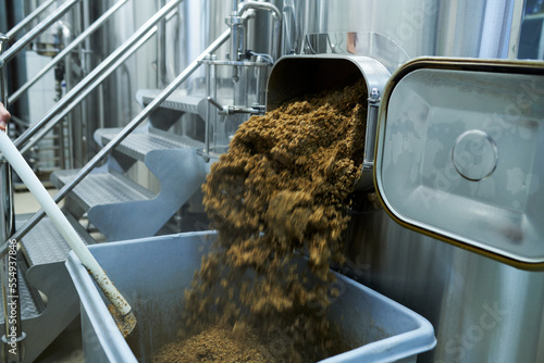 Fotografi Brewery worker removing spent grain from tank