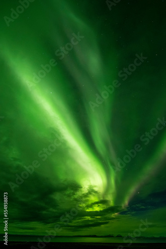 Aurora borealis, bands of bright green light flashing across the night sky over the horizon; Iceland