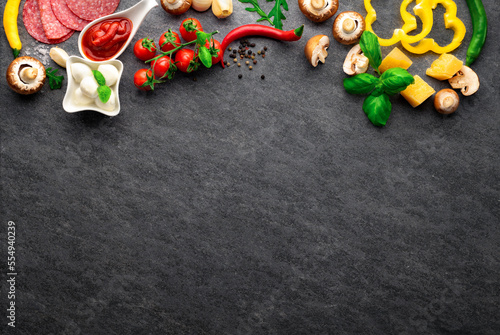Set ingredients for cooking italian pizza on a dark stone background with copy space, top view
