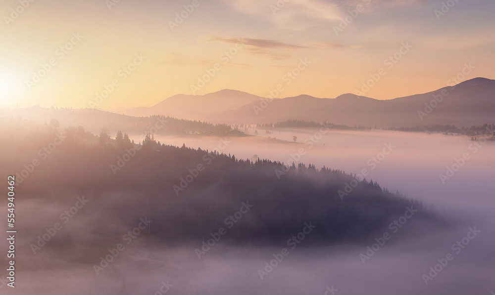 Panoramic view of Scenic misty morning in mountains. Amazing nayure landscape. Mountain valley with morning fog and silhouettes of Mountain ranges. Carpathian mountains. Ukraine. Creative image Panoramic view of Scenic misty morning in mountains. Amazing nayure landscape. Mountain valley with morning fog and silhouettes of Mountain ranges. Carpathian mountains. Ukraine. Creative image