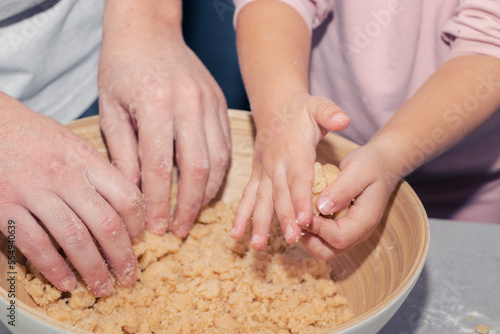 girl's hands kneading cookie dough with her father in a bowl