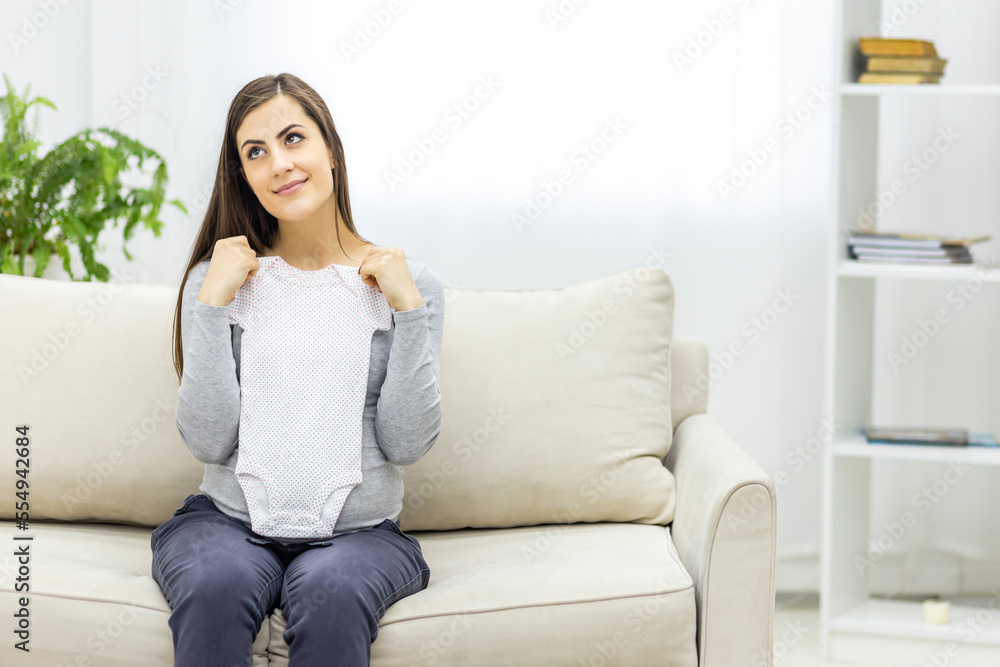 Photo of pregnant woman holding child small clothes. Photo of pregnant woman holding child small clothes.