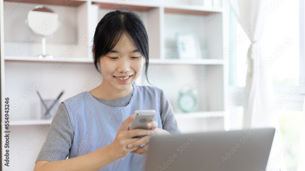 Asian woman having fun playing games on mobile phone, Play games on the sofa in the living room on weekends, Resting at home, Comfort zone, Touch screen mobile phone. Asian woman having fun playing games on mobile phone, Play games on the sofa in the living room on weekends, Resting at home, Comfort zone, Touch screen mobile phone.