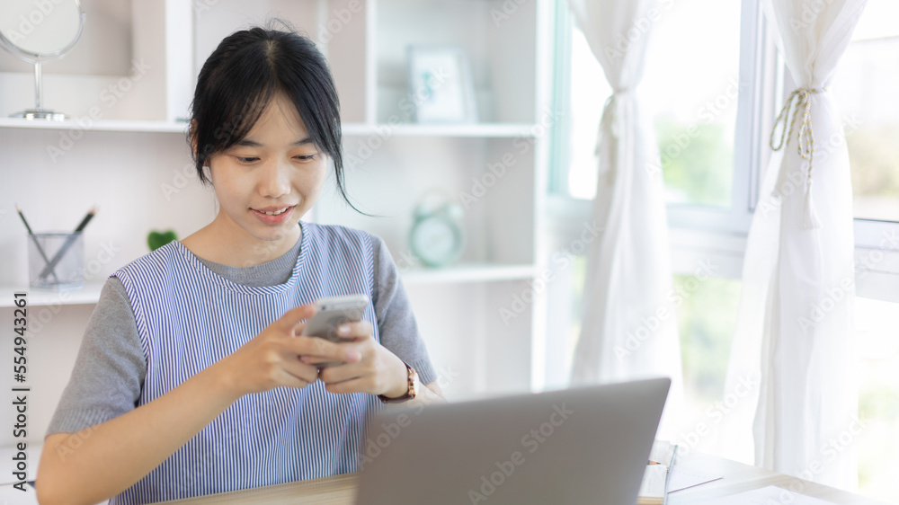 Asian woman having fun playing games on mobile phone, Play games on the sofa in the living room on weekends, Resting at home, Comfort zone, Touch screen mobile phone. Asian woman having fun playing games on mobile phone, Play games on the sofa in the living room on weekends, Resting at home, Comfort zone, Touch screen mobile phone.