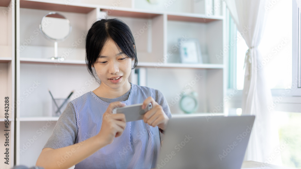 Asian woman having fun playing games on mobile phone, Play games on the sofa in the living room on weekends, Resting at home, Comfort zone, Touch screen mobile phone. Asian woman having fun playing games on mobile phone, Play games on the sofa in the living room on weekends, Resting at home, Comfort zone, Touch screen mobile phone.