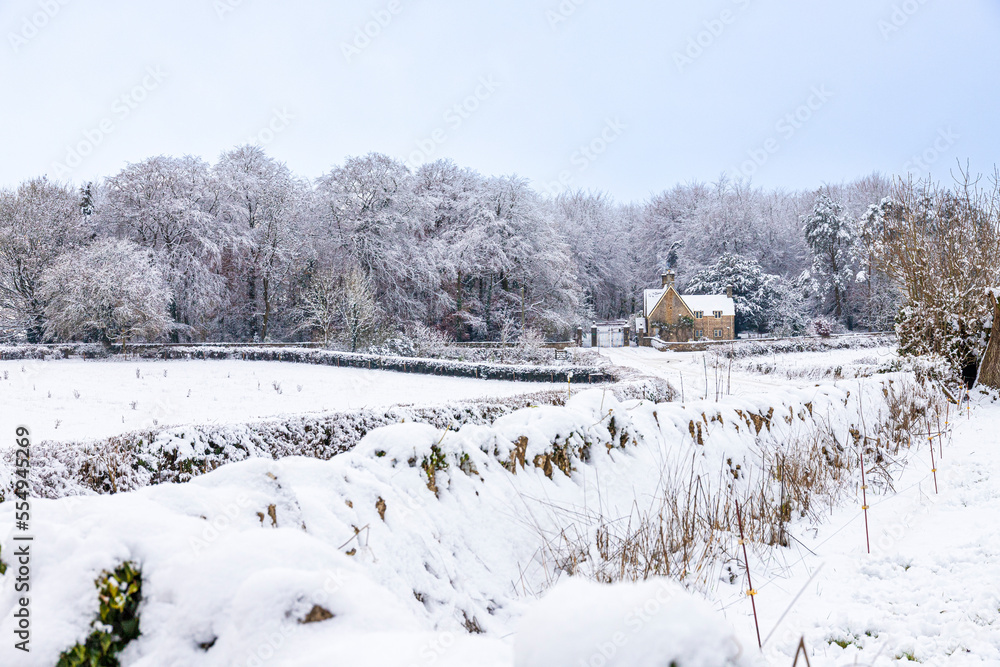 Early winter snow on the lodge and gates to Miserden Park near the Cotswold village of Winstone, Gloucestershire, England UK