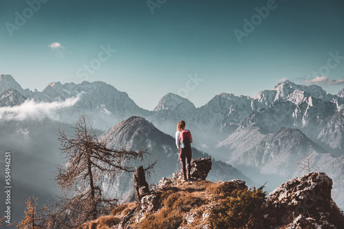 Scenic mountain view and one lonely woman hiker standing at a view point looking at the Alps