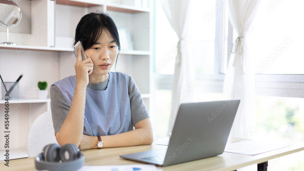 Finance workers are reviewing the company's financial data on a laptop and using smartphones to communicate or chat with the team during social distances, Working alone in a private office. Finance workers are reviewing the company's financial data on a laptop and using smartphones to communicate or chat with the team during social distances, Working alone in a private office.