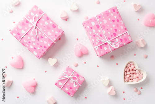 Saint Valentine's Day concept. Top view photo of pink present boxes heart shaped plate with sprinkles marshmallow and candles on isolated white background © ActionGP