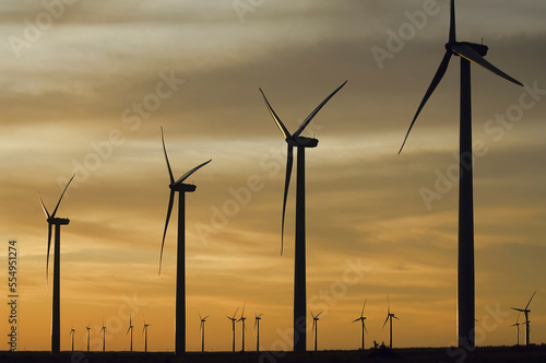 Silhouetted wind turbines on a wind farm at sunset. Windmill farms are badly fragmenting habitat for grassland birds; Laverne, Oklahoma, United States of America photo