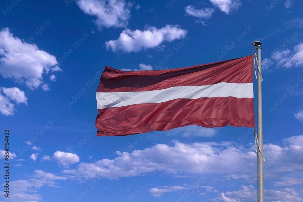 The flag of the state of Latvia on the background of the sunny sky.