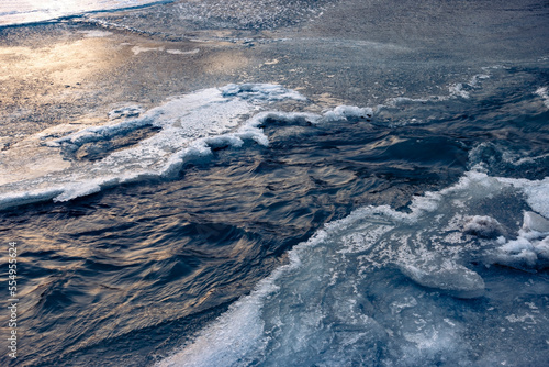 Frozen ice and snow in river side. Spring thawed patch in the ice