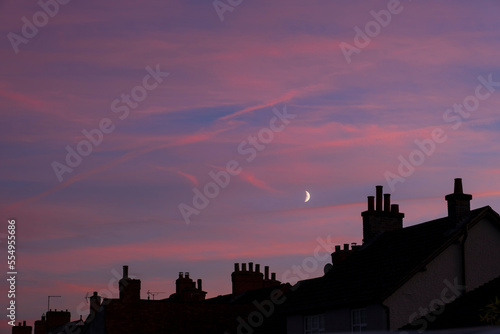 Sunset with crescent moon over rooftops. photo