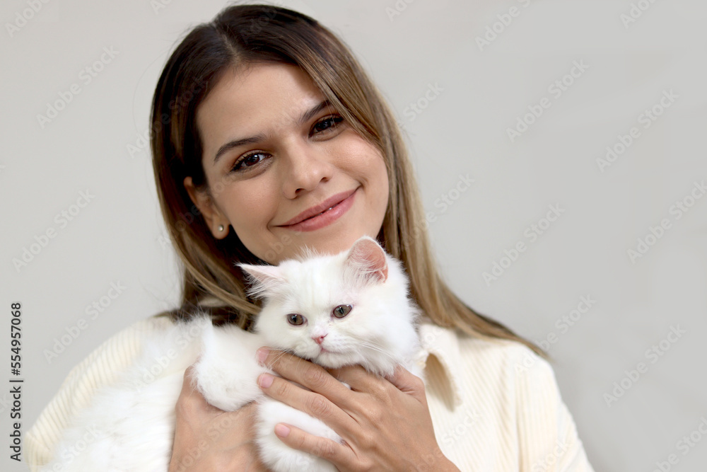 Portrait of young happy smiling woman holding cute white Persian cat, happy beautiful lady playing with fluffy pet, girl hugging her adorable long hair kitty with love Portrait of young happy smiling woman holding cute white Persian cat, happy beautiful lady playing with fluffy pet, girl hugging her adorable long hair kitty with love