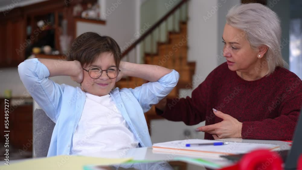 Sad schoolboy closing ears with hands as angry woman shouting scolding. Portrait of exhausted tired Caucasian son with dissatisfied mature mother doing homework Sad schoolboy closing ears with hands as angry woman shouting scolding. Portrait of exhausted tired Caucasian son with dissatisfied mature mother doing homework