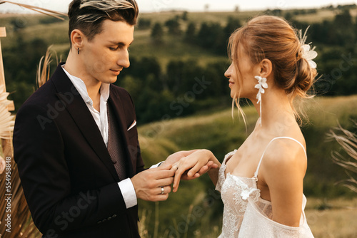 Newlyweds at the wedding ceremony. The groom puts on the bride's wedding ring