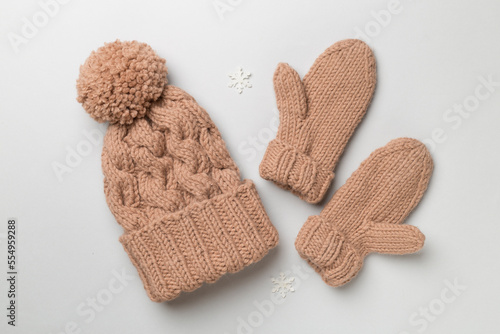 Brown winter hat and mittens on color background. Top view