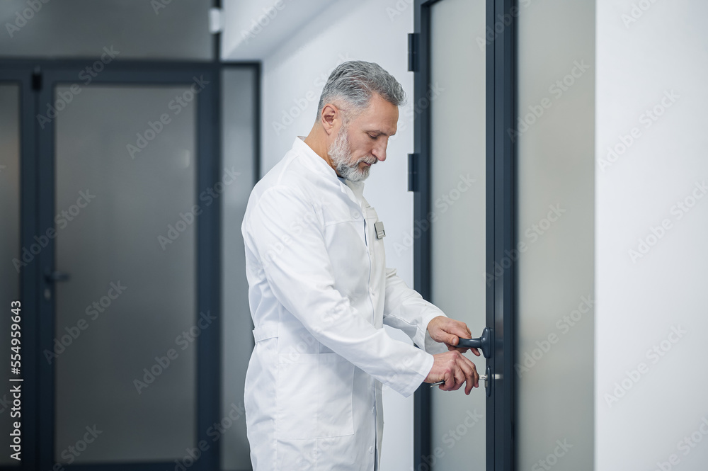 Mature male doctor locking his office