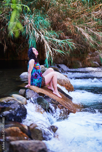 latin mid adult woman sitting on a stone in the Cochiguaz river with eyes closed enjoying the climate and nature of the Valle del Elqui, Cochiguaz photo