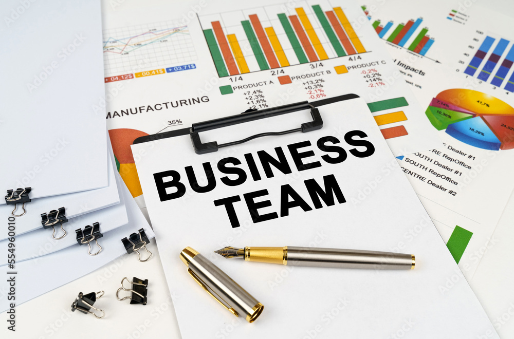 On the table among financial graphs and charts lies a tablet with the inscription - Business team On the table among financial graphs and charts lies a tablet with the inscription - Business team
