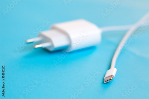 White type C charger on blue background. USB type C port cable for charging to the smartphone on blue background. EU law to force USB-C chargers. 