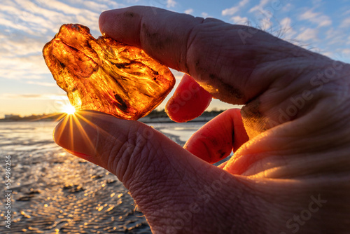 male hand holds recently found amber against the sun photo