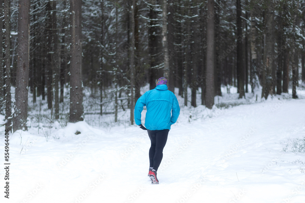 A man runs in the winter forest.Doing sports in winter.
